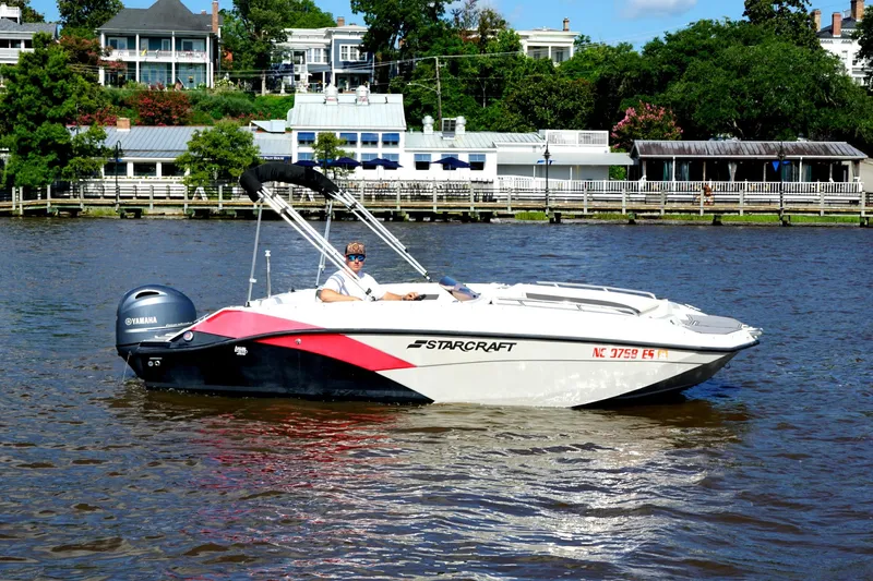 Slide: The Image of 2021 Starcraft SVX 171 OB boat on a river, with scenic waterfront background. - 14