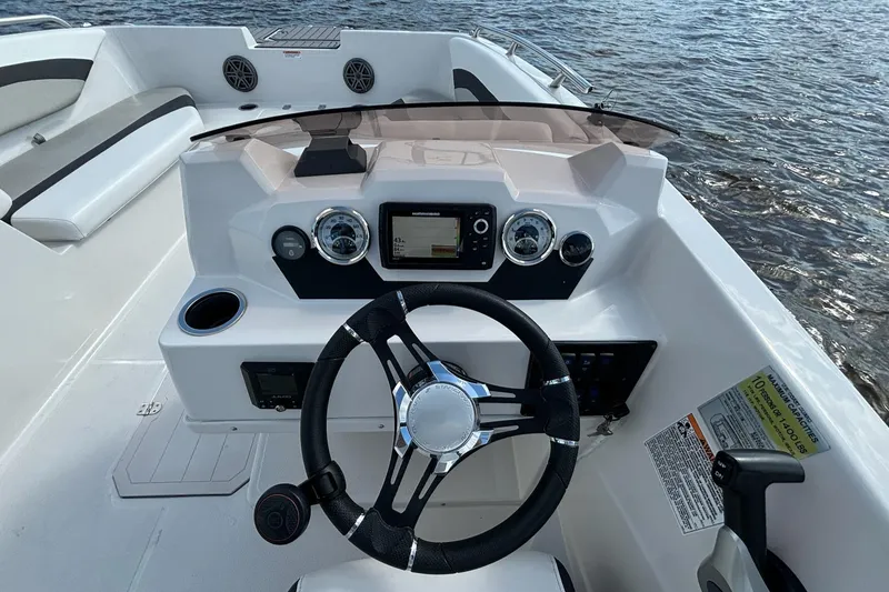 Slide: The Image of 2021 Starcraft SVX 171 OB boat dashboard with steering wheel and controls on water. - 9