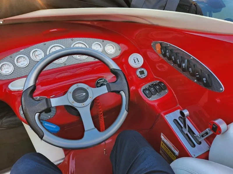 Slide: The Image of 2003 Baja 24 H2X Boss boat dashboard with red accents and steering wheel. - 2