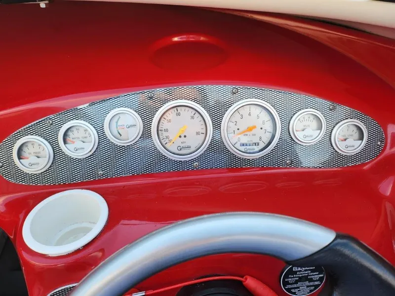 Slide: The Image of Dashboard of a 2003 Baja 24 H2X Boss boat with gauges and red trim. - 3