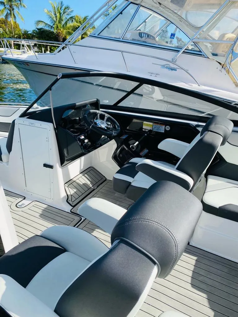 Slide: The Image of 2022 Yamaha Boats 212S interior with sleek black and white seating, docked near palm trees. - 2