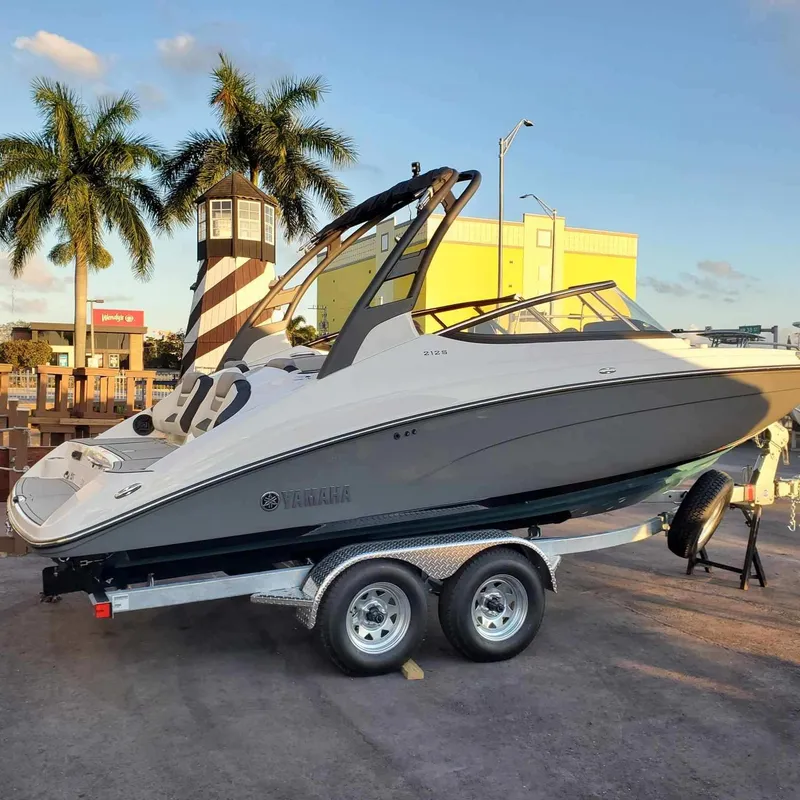Slide: The Image of 2022 Yamaha Boats 212S on trailer, parked near palm trees and lighthouse. - 3