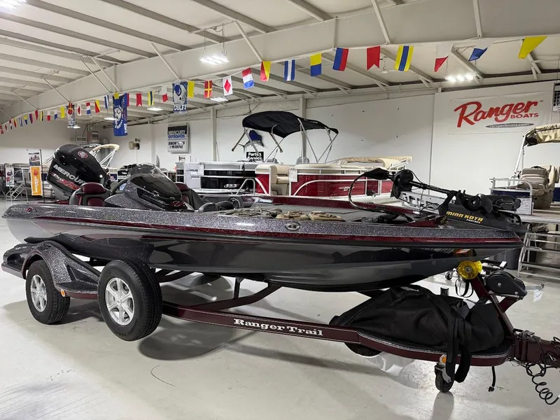 Slide: The Image of 2014 Ranger 118c boat on trailer in showroom with flags above. - 3