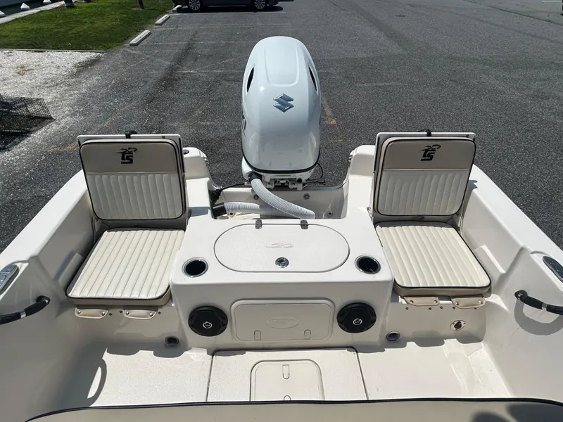 Slide: The Image of 2022 Carolina Skiff 19 LS boat interior with seating and motor, parked on asphalt. - 12