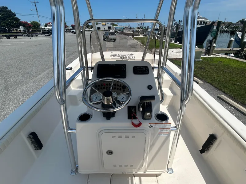 Slide: The Image of 2022 Carolina Skiff 19 LS boat console with steering wheel and controls, docked near marina. - 16