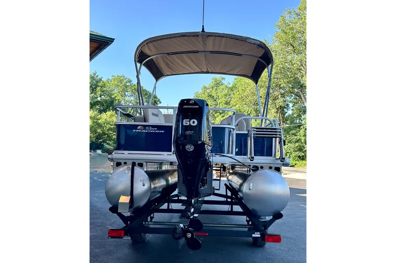 Slide: The Image of 2025 Sun Tracker Bass Buggy 18 DLX pontoon boat with Mercury 60 engine, parked outdoors. - 3