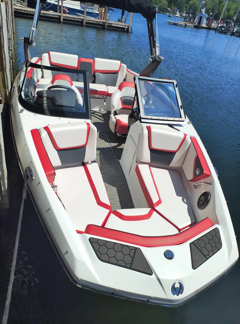 Slide: The Image of 2023 Scarab 195 ID boat with red and white seating, docked on a sunny day. - 7