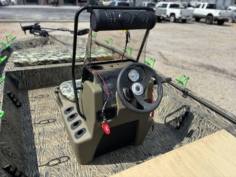 Slide: The Image of 2025 Tracker GRIZZLY® 1860 CC boat interior with steering console and camo design. - 13