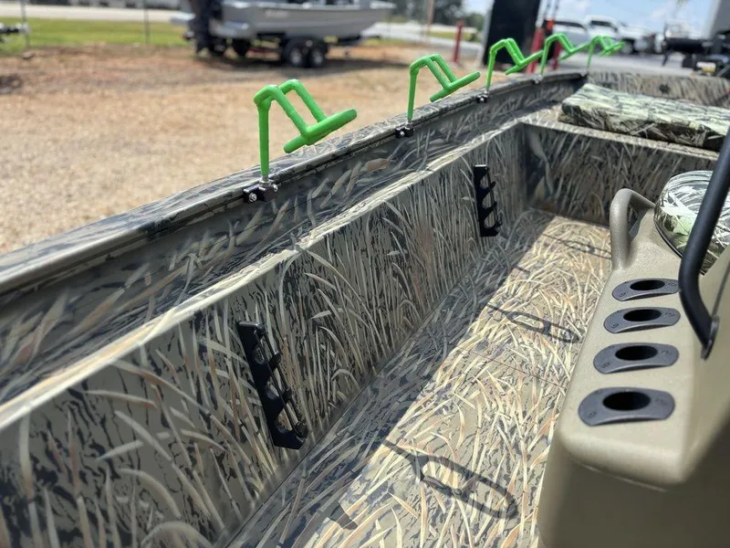 Slide: The Image of 2025 Tracker GRIZZLY® 1860 CC boat interior with camo design and green rod holders. - 17