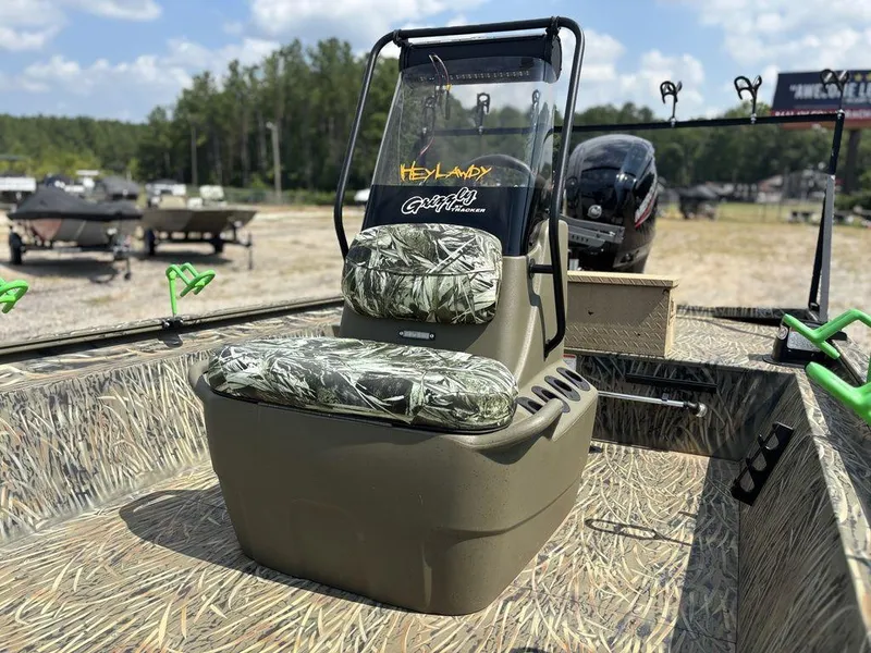Slide: The Image of 2025 Tracker GRIZZLY® 1860 CC boat with camo seating and console, parked outdoors. - 7