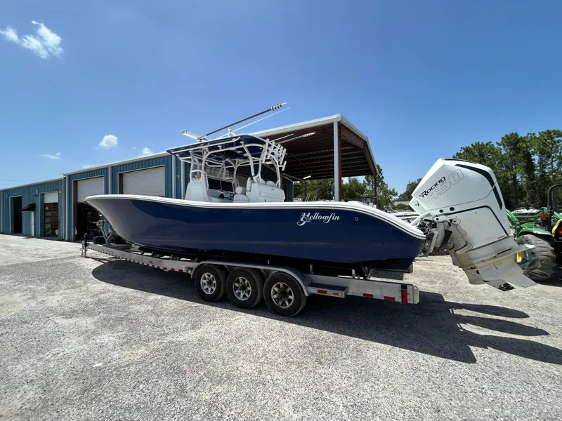 Slide: The Image of 2019 Yellowfin 36 Offshore boat on trailer, parked near blue storage units. - 3
