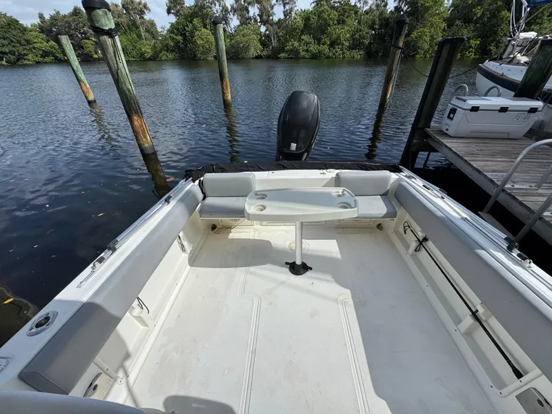Slide: The Image of 2005 Hydra-Sports Lightning 230 WA boat interior with seating and table, docked by a serene waterway. - 5