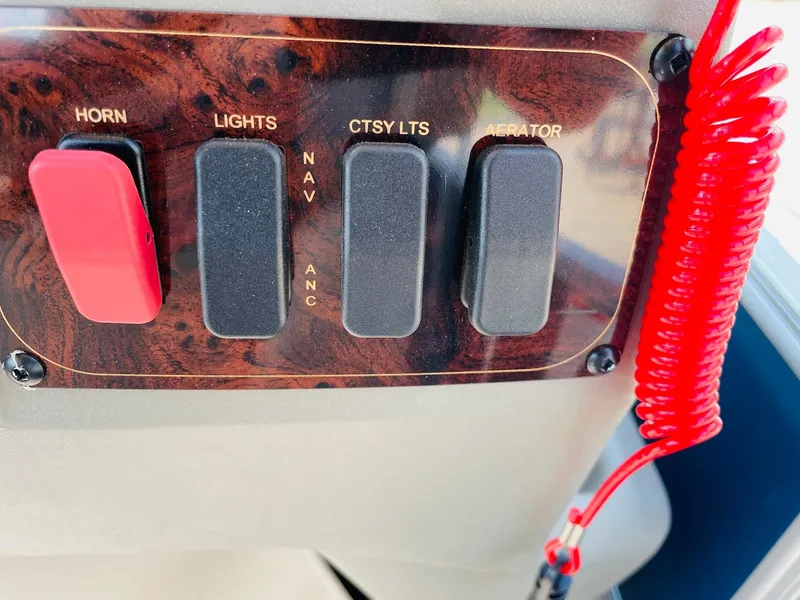 Slide: The Image of Control panel of 2025 Sun Tracker Bass Buggy 18 DLX with switches and red coiled cord. - 21