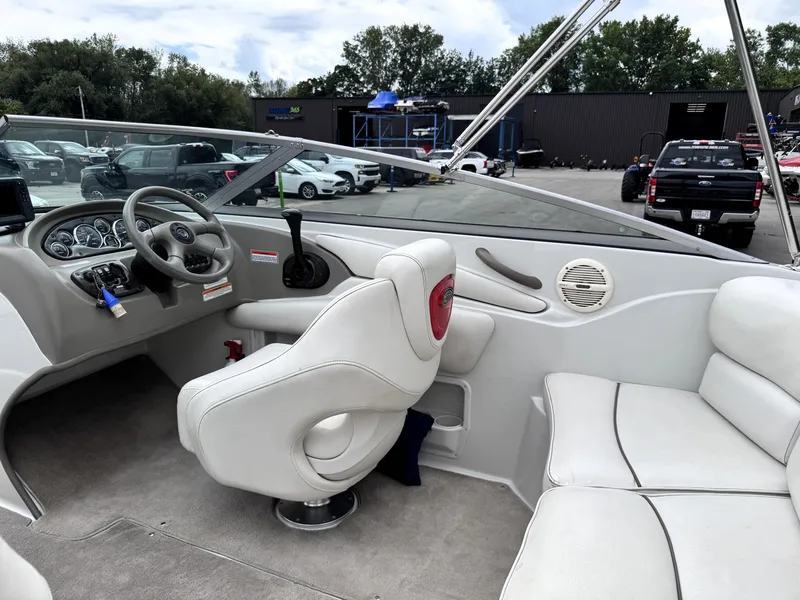 Slide: The Image of 2004 Crownline 206 LS boat interior with steering wheel and seating, parked outdoors. - 12