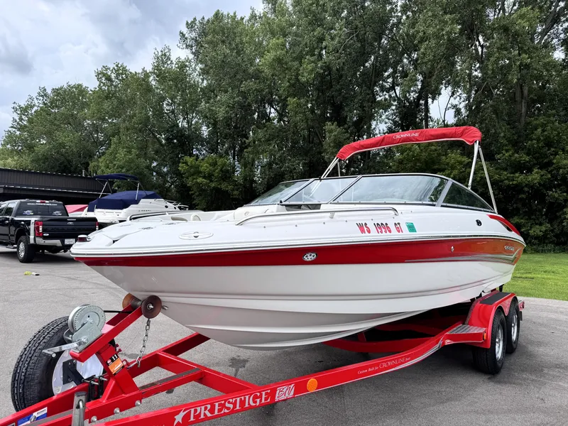 Slide: The Image of 2004 Crownline 206 LS boat on red trailer, parked outdoors with trees in background. - 3