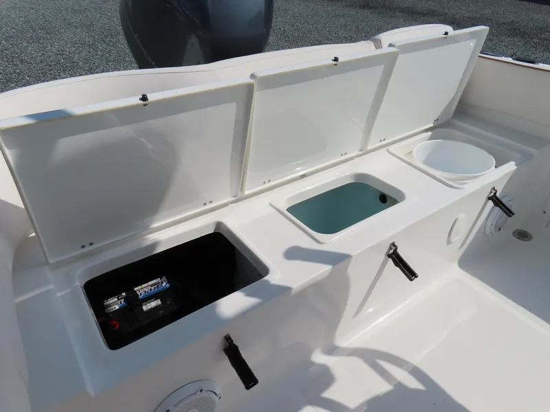 Slide: The Image of 2021 Sea Hunt Ultra 219 boat storage compartments with open lids and visible battery. - 32