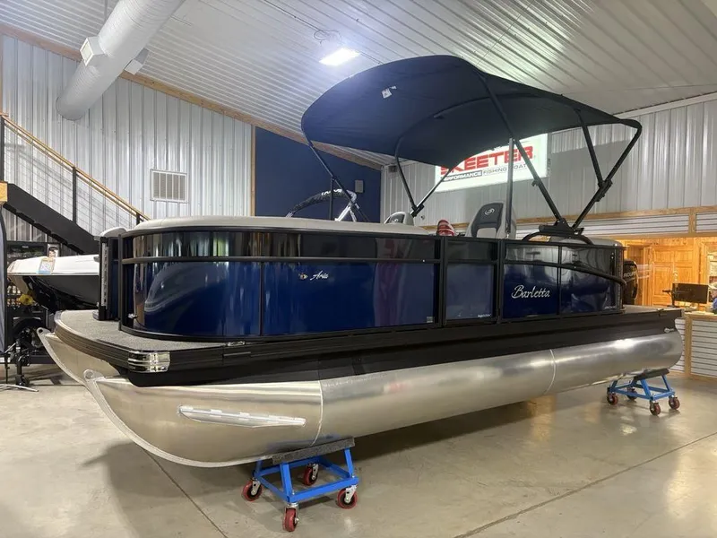 Slide: The Image of 2025 Barletta A20QC pontoon boat in showroom, featuring sleek design and blue exterior. - 2