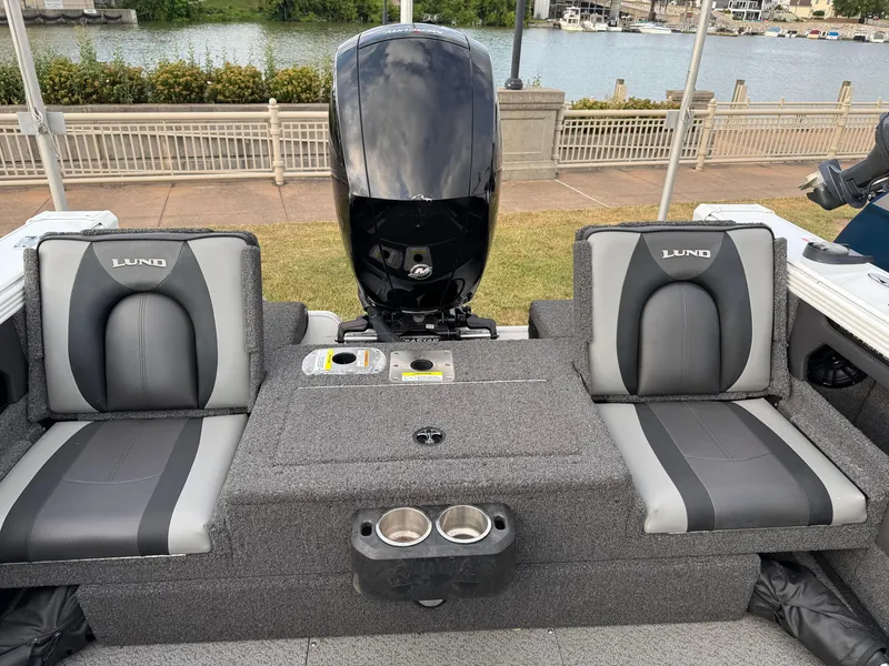 Slide: The Image of 2021 Lund 1875 Tyee boat interior with dual seats and outboard motor by the water. - 19