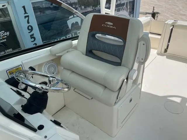 Slide: The Image of 2019 Cobia 240 Dual Console boat helm with cushioned captain's chair and steering wheel. - 4