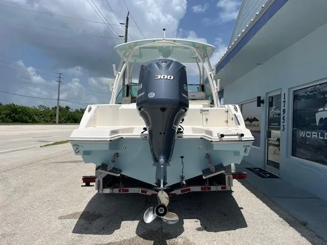Slide: The Image of 2019 Cobia 240 Dual Console boat with 300 HP engine, parked outside a building. - 7