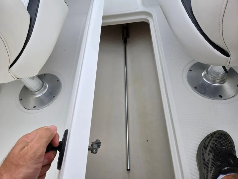 Slide: The Image of 2012 Sea Ray 190 Sport boat interior storage compartment with seats and a metal rod. - 12