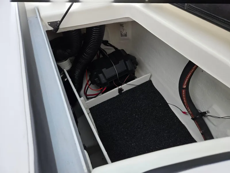 Slide: The Image of 2012 Sea Ray 190 Sport boat interior storage compartment with wiring and battery. - 22