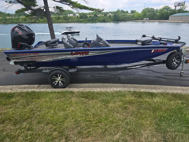 Slide: The Image of 2021 Lowe Stinger 188 boat on trailer by a riverbank. - 10