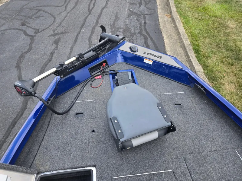 Slide: The Image of 2021 Lowe Stinger 188 boat deck with trolling motor and seat, parked on asphalt. - 16