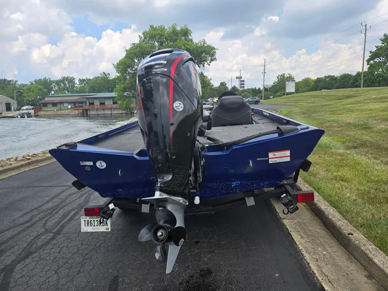 Slide: The Image of 2021 Lowe Stinger 188 boat with outboard motor on a trailer, parked near a lake. - 2