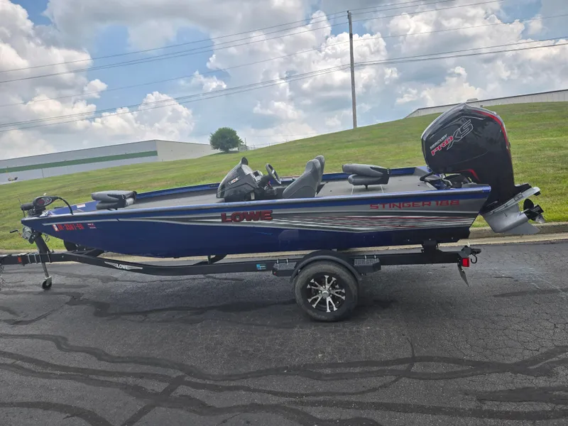 Slide: The Image of 2021 Lowe Stinger 188 boat on trailer, parked outdoors under cloudy sky. - 4