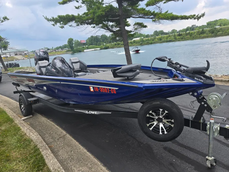 Slide: The Image of 2021 Lowe Stinger 188 boat on trailer by a lake, under a cloudy sky. - 9