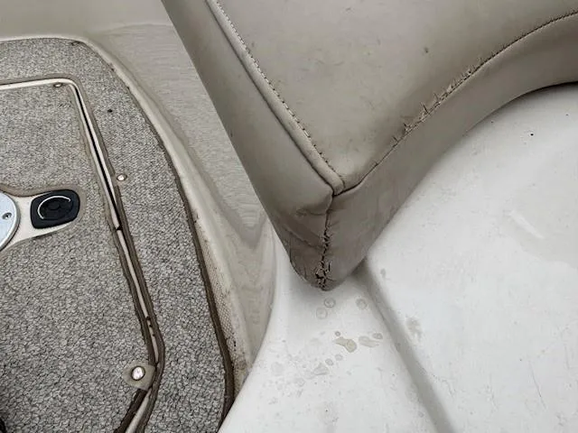 Slide: The Image of 2004 Sea Ray 240 Sundeck interior showing worn upholstery and carpeted flooring. - 12