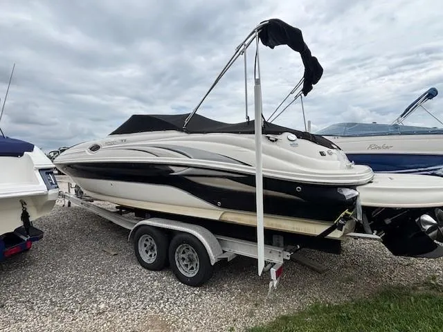 Slide: The Image of 2004 Sea Ray 240 Sundeck boat on trailer, parked outdoors under cloudy sky. - 2