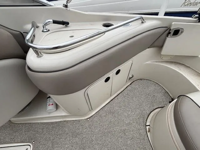Slide: The Image of 2004 Sea Ray 240 Sundeck interior with beige seating and storage compartments. - 9