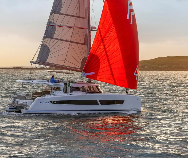 Slide: The Image of 2025 Fountaine Pajot NEW 41 catamaran sailing with vibrant red sails at sunset. - 4