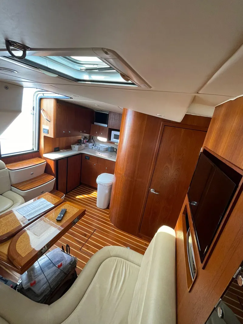 Slide: The Image of Interior of 2008 Tiara Yachts 3800 Open, featuring wood finishes and a compact kitchen area. - 13