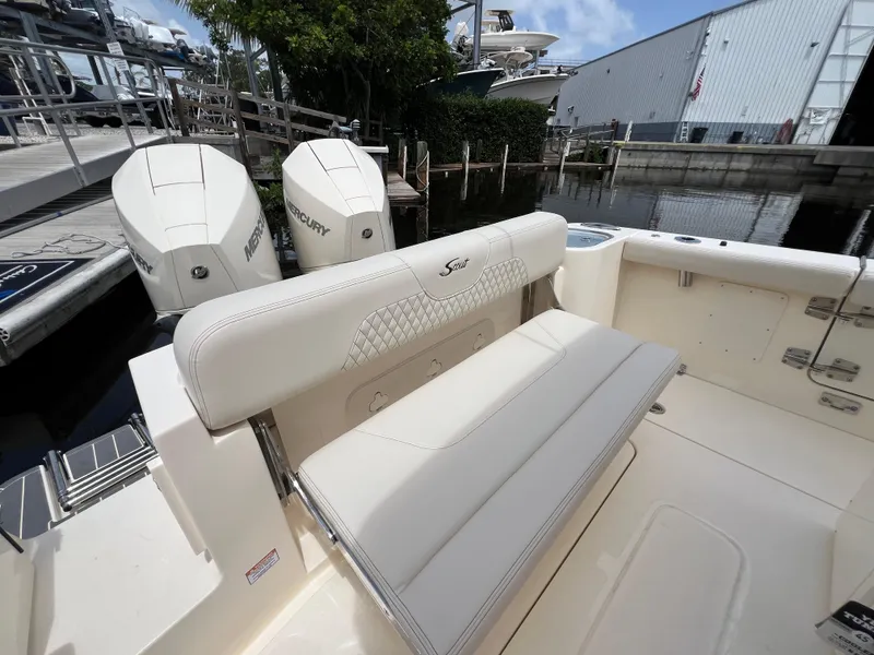 Slide: The Image of 2026 Scout 260 LXF boat interior with cushioned seating and Mercury engines at dock. - 14