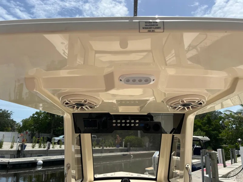 Slide: The Image of 2026 Scout 260 LXF boat hardtop with speakers and control panel, docked under clear sky. - 18