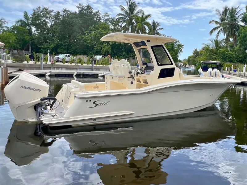 Slide: The Image of 2026 Scout 260 LXF boat docked on calm water, surrounded by lush greenery and palm trees. - 2