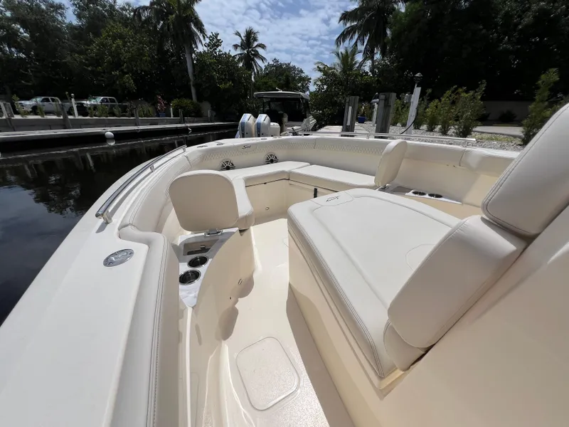 Slide: The Image of 2026 Scout 260 LXF boat interior with luxurious seating and cup holders, docked near lush greenery. - 29