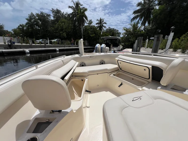 Slide: The Image of 2026 Scout 260 LXF boat interior with seating and storage, docked near lush greenery. - 30