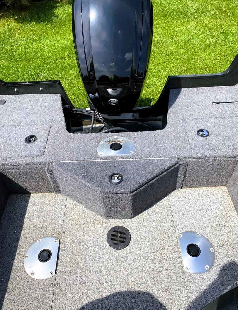 Slide: The Image of 2022 Tracker Pro Guide V-16 SC boat interior with motor and carpeted deck. - 6