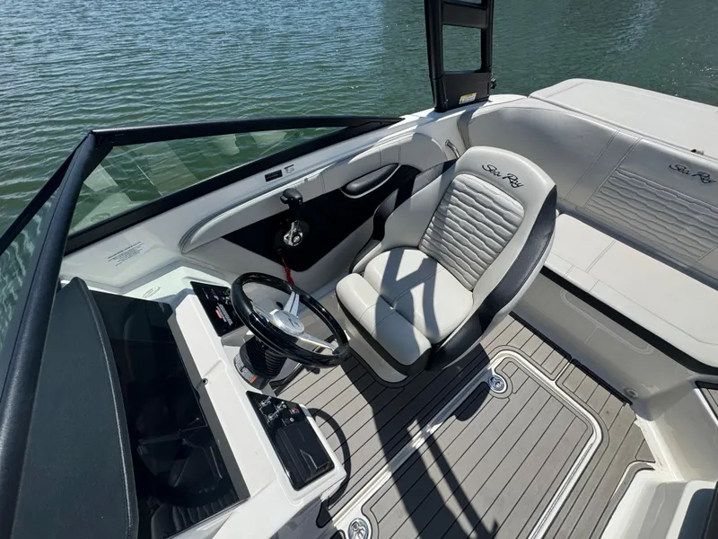Slide: The Image of 2023 Sea Ray SPX 190 boat interior with steering wheel and seating, on calm water. - 10