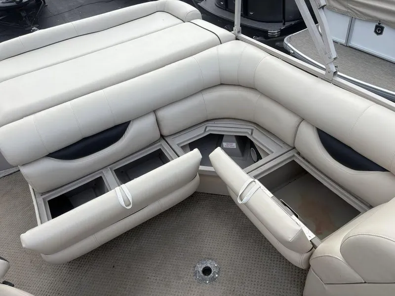 Slide: The Image of 2006 Sylvan 8522 Signature boat interior with open storage compartments and beige seating. - 7