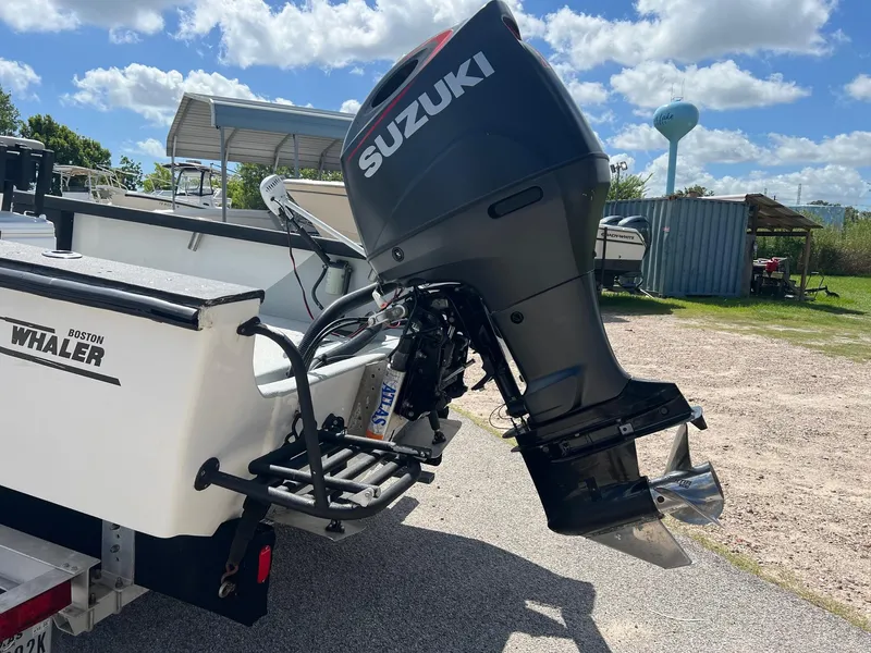 Slide: The Image of 1989 Boston Whaler 23 Guardian with Suzuki outboard motor, parked outdoors under a blue sky. - 4