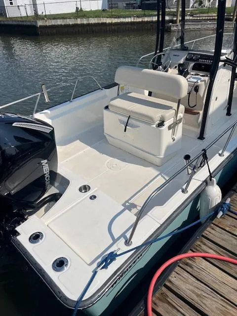 Slide: The Image of 2024 Boston Whaler 210 Montauk boat docked, showcasing spacious deck and seating. - 2