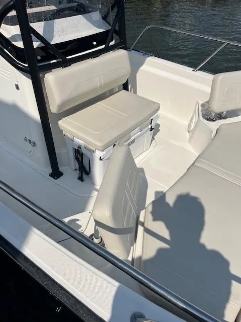 Slide: The Image of 2024 Boston Whaler 210 Montauk boat interior with seating and storage, docked on water. - 4