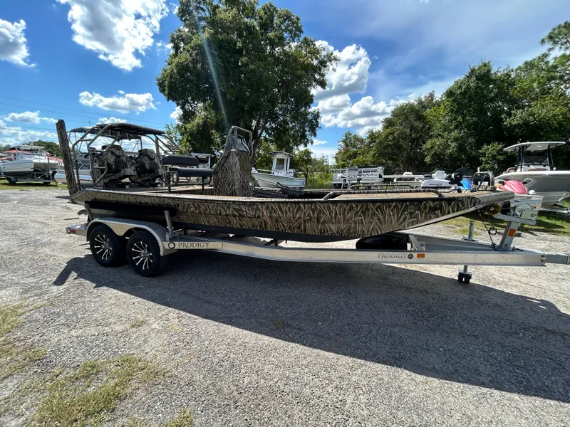 Slide: The Image of 2023 Prodigy 2070 boat on trailer, camo design, parked outdoors under blue sky. - 5