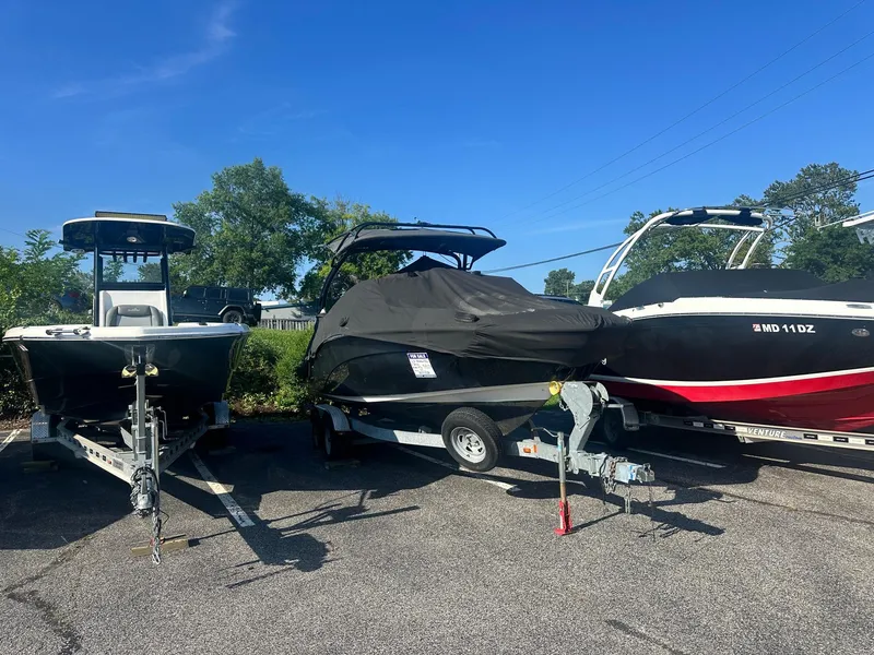 Slide: The Image of 2016 Yamaha Boats 242 Limited S E-Series covered on trailer, parked between two other boats. - 8