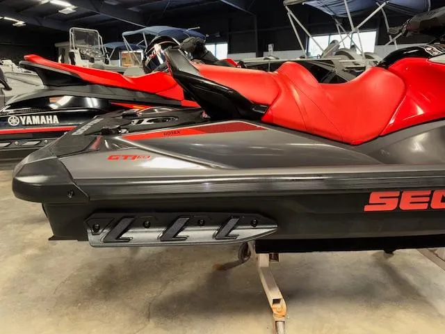 Slide: The Image of 2023 Sea-Doo GTI SE jet ski with red seat and sleek design in showroom. - 14
